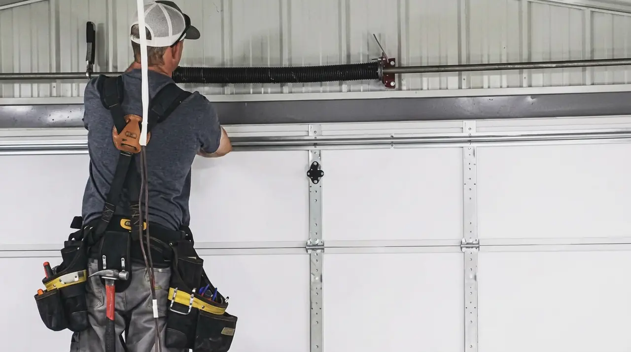 Technician working on a sectional garage door spring system